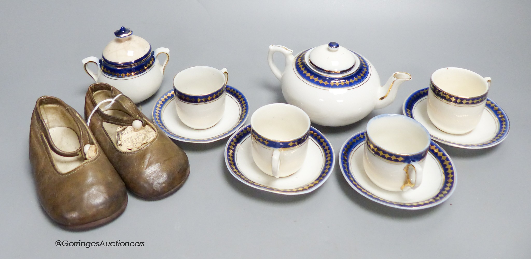 A child's tea set and a pair of leather shoes